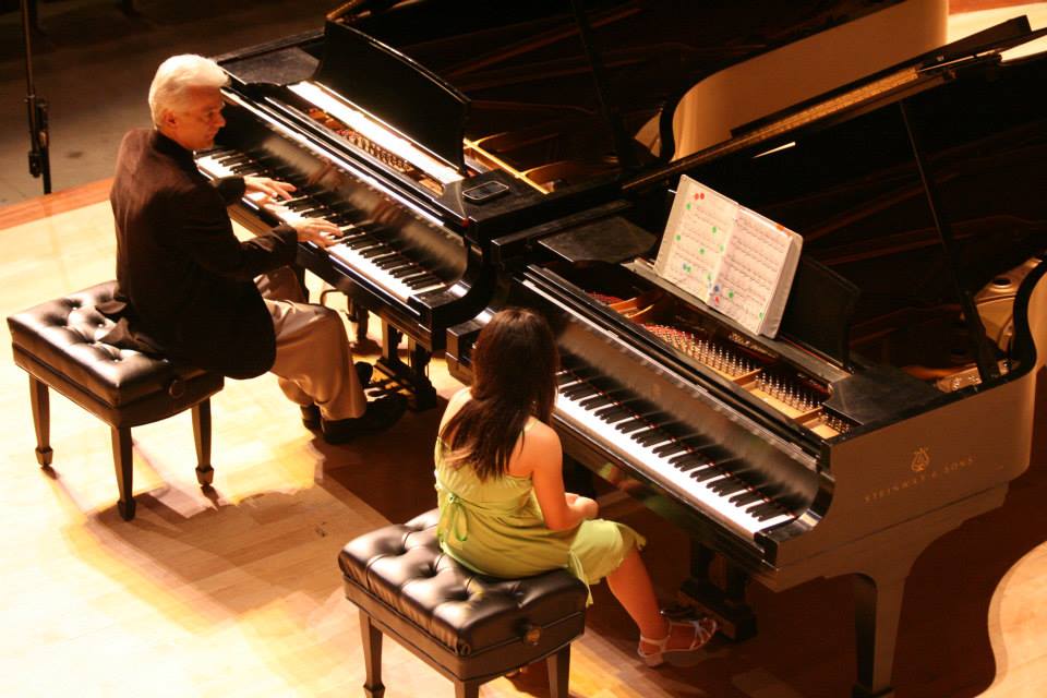 A piano teacher working with a student.